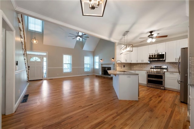 kitchen with white cabinets, backsplash, hanging light fixtures, and appliances with stainless steel finishes