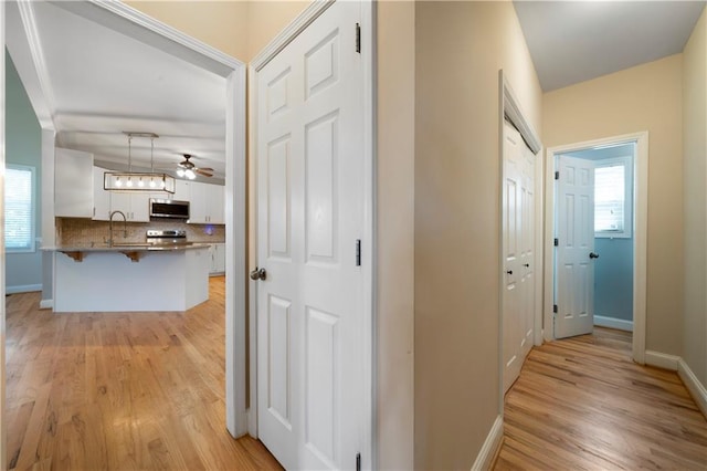 hallway with light hardwood / wood-style flooring and sink