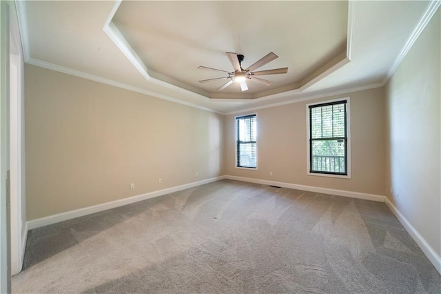 carpeted empty room with ceiling fan, ornamental molding, and a tray ceiling