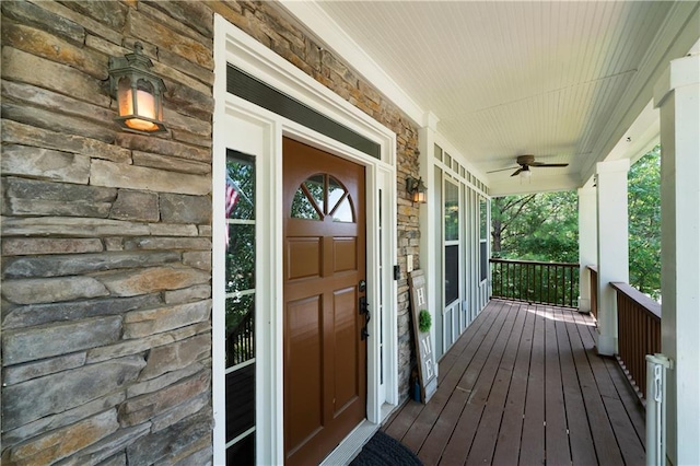 view of exterior entry with ceiling fan and a porch