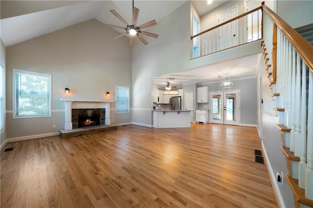 unfurnished living room with light hardwood / wood-style floors, high vaulted ceiling, and ceiling fan