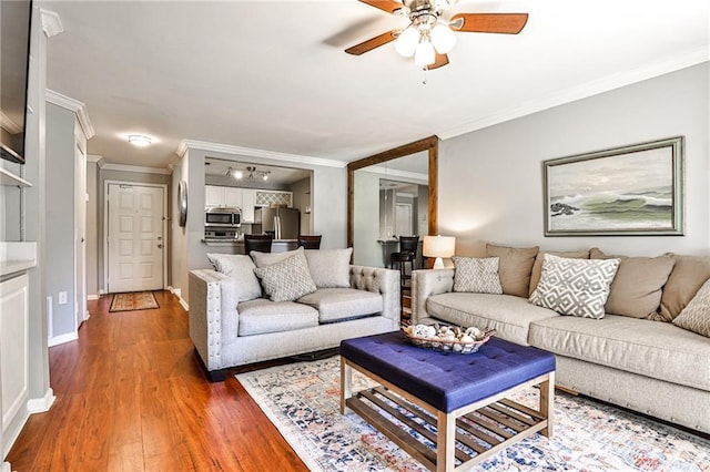 living room featuring dark hardwood / wood-style flooring, ceiling fan, and ornamental molding