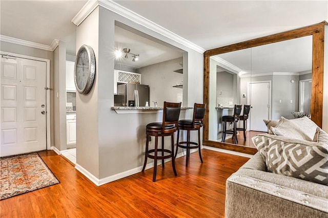 interior space with stainless steel fridge with ice dispenser, hardwood / wood-style flooring, and ornamental molding