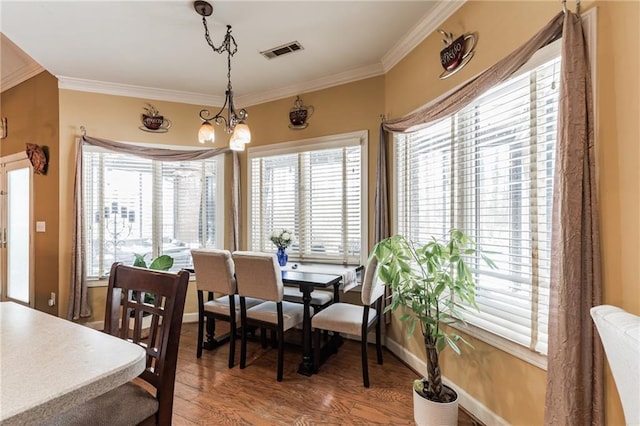 dining area featuring a chandelier, hardwood / wood-style flooring, and crown molding