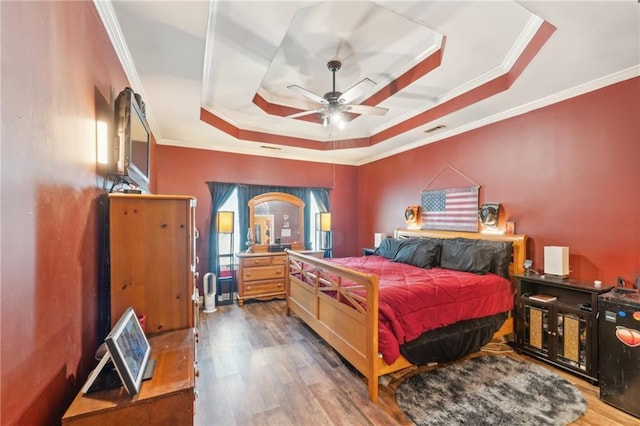 bedroom featuring a tray ceiling, dark hardwood / wood-style flooring, ceiling fan, and crown molding