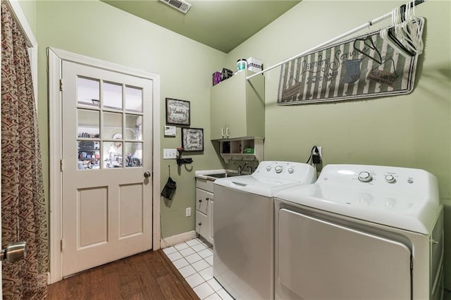 clothes washing area featuring sink, cabinets, light wood-type flooring, and independent washer and dryer