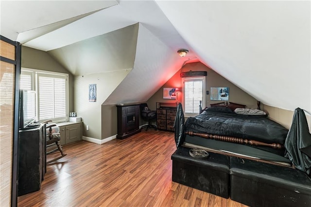 bedroom with hardwood / wood-style flooring, vaulted ceiling, and multiple windows