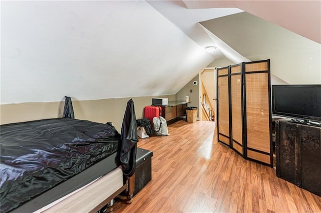 bedroom with light hardwood / wood-style floors and lofted ceiling