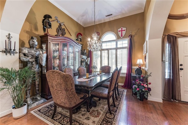 dining space featuring hardwood / wood-style floors, an inviting chandelier, and crown molding