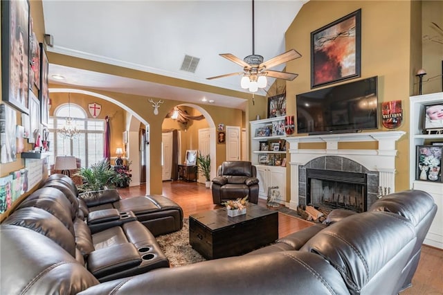 living room with a fireplace, light wood-type flooring, ceiling fan with notable chandelier, and vaulted ceiling