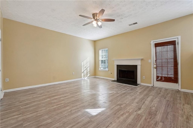 unfurnished living room with ceiling fan, light wood-type flooring, and a textured ceiling