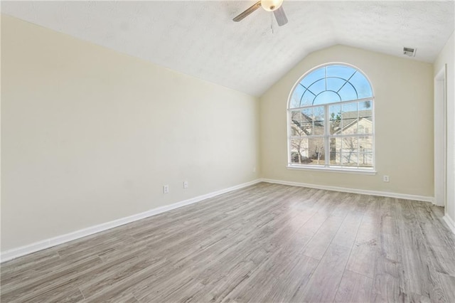 empty room featuring ceiling fan, vaulted ceiling, and light hardwood / wood-style flooring