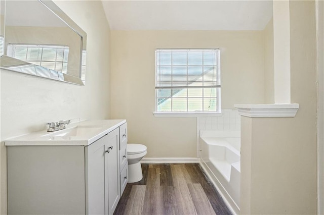 bathroom with lofted ceiling, vanity, a bathtub, toilet, and hardwood / wood-style flooring