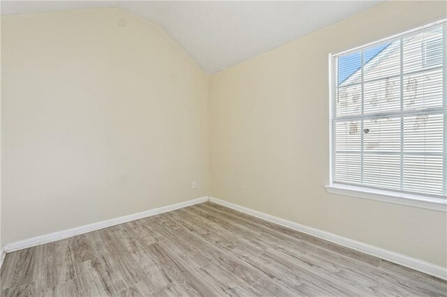 spare room featuring lofted ceiling and light hardwood / wood-style flooring