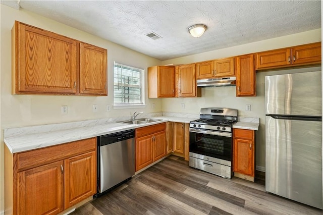 kitchen featuring sink, a textured ceiling, dark hardwood / wood-style floors, and stainless steel appliances