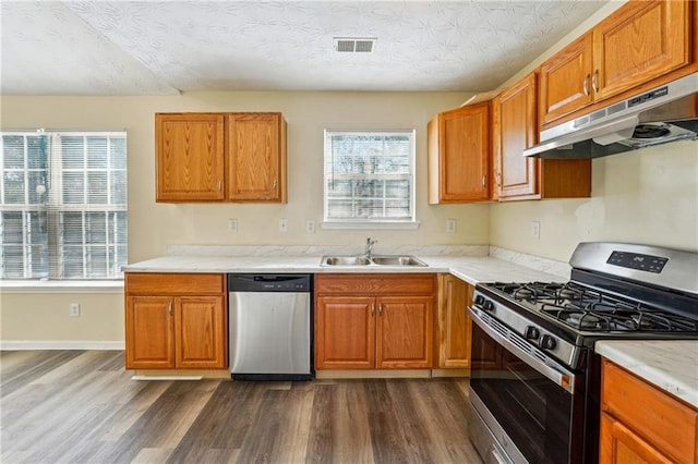 kitchen featuring a textured ceiling, dark hardwood / wood-style flooring, stainless steel appliances, a healthy amount of sunlight, and sink