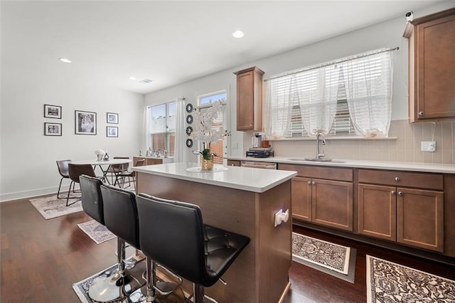 kitchen featuring sink, a center island, dark hardwood / wood-style flooring, backsplash, and a breakfast bar