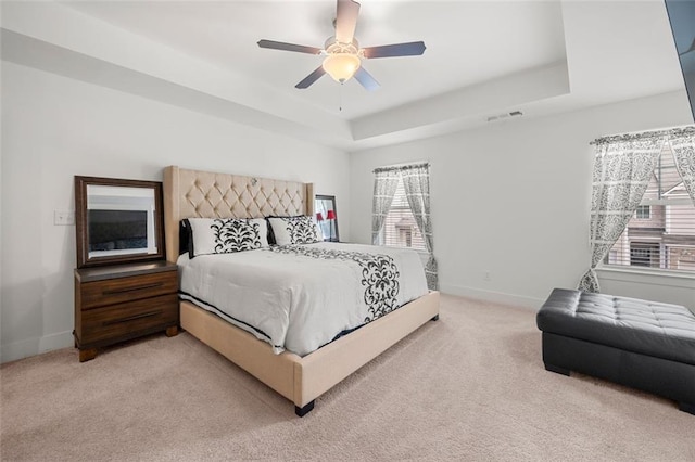 carpeted bedroom featuring a raised ceiling and ceiling fan