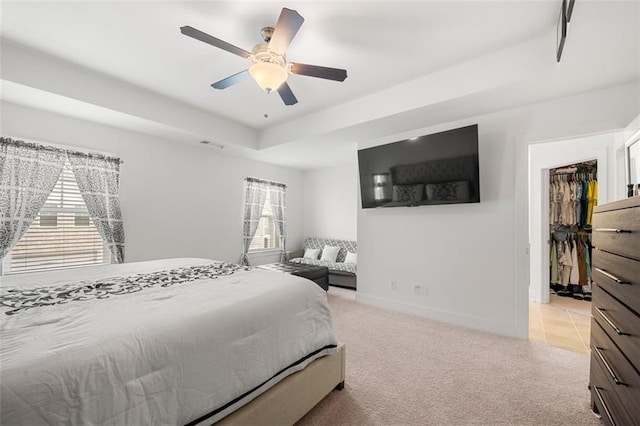 carpeted bedroom featuring multiple windows, a closet, a raised ceiling, and ceiling fan