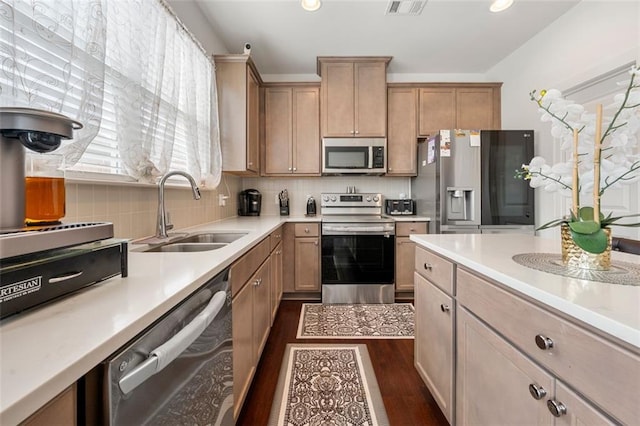 kitchen with light brown cabinets, backsplash, dark wood-type flooring, sink, and appliances with stainless steel finishes