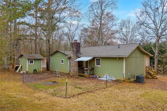 back of house with cooling unit, a shed, and a lawn