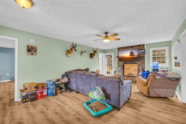 living room with ceiling fan, a textured ceiling, and light wood-type flooring