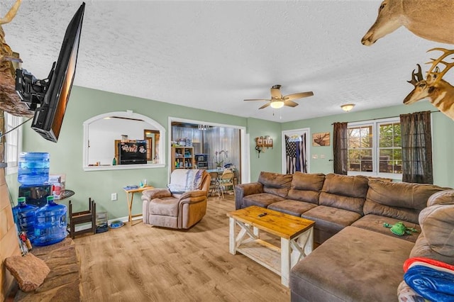 living room with ceiling fan, light hardwood / wood-style flooring, and a textured ceiling