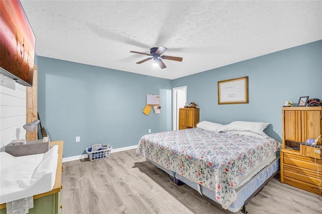 bedroom with ceiling fan, a textured ceiling, and light hardwood / wood-style floors