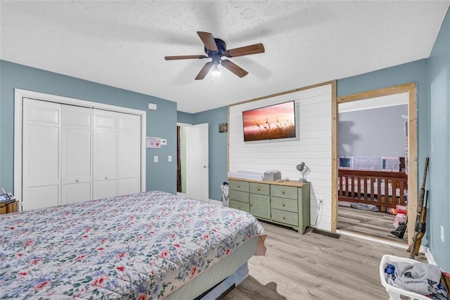 bedroom with ceiling fan, a closet, light hardwood / wood-style floors, and a textured ceiling