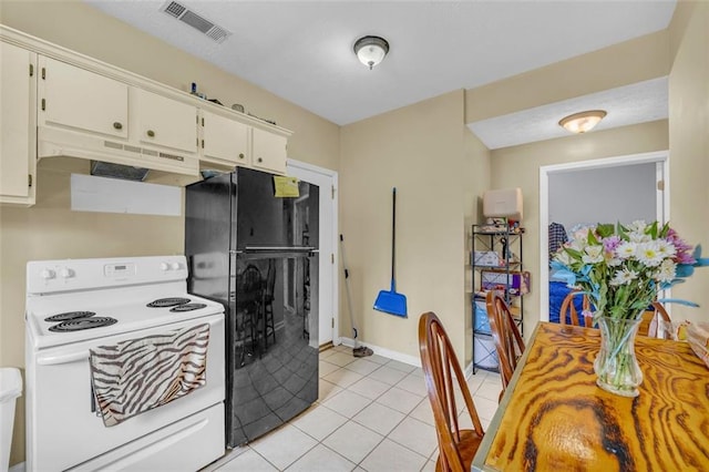 kitchen featuring black fridge, white electric range oven, light tile patterned floors, and white cabinets