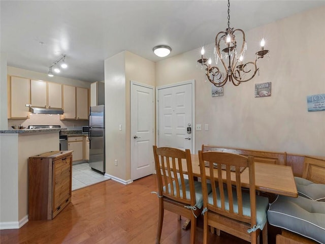 dining space with light hardwood / wood-style flooring and a notable chandelier