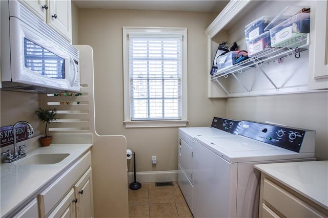 clothes washing area with washing machine and clothes dryer, sink, a wealth of natural light, and light tile floors