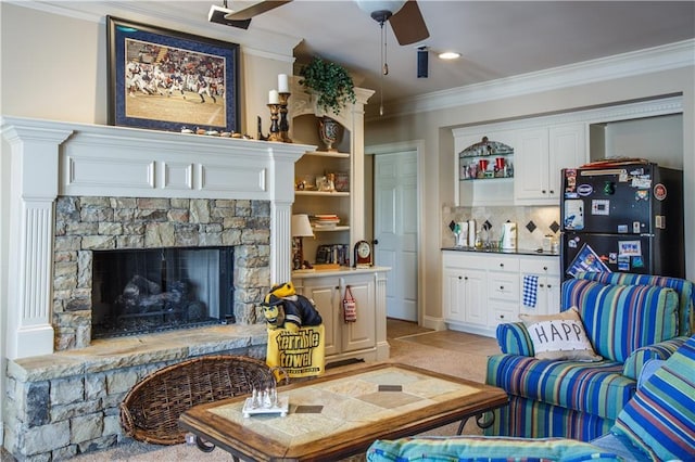 living room with ceiling fan, crown molding, a stone fireplace, and light tile floors