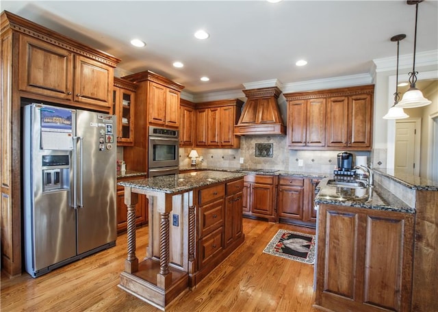 kitchen with stainless steel appliances, a center island, light hardwood / wood-style flooring, hanging light fixtures, and custom range hood