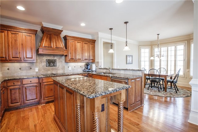 kitchen with an inviting chandelier, pendant lighting, a center island, light hardwood / wood-style floors, and dishwasher