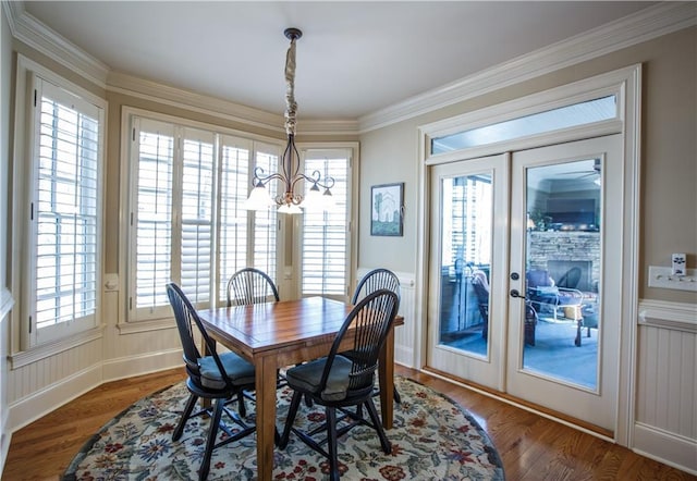 dining area with a wealth of natural light, crown molding, an inviting chandelier, and dark hardwood / wood-style flooring