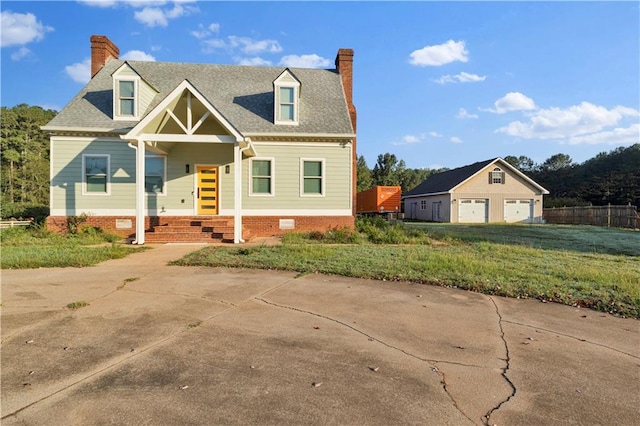 new england style home featuring covered porch, a garage, an outdoor structure, and a front lawn