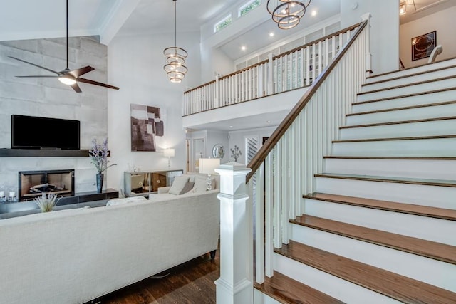 6144 Scott Dr, Flowery Branch, GA 30542 - stairway with a towering ceiling, a fireplace, wood finished floors, ceiling fan, and a chandelier