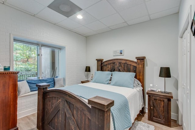 6144 Scott Dr, Flowery Branch, GA 30542 - bedroom with a paneled ceiling, light wood-type flooring, brick wall, and baseboards