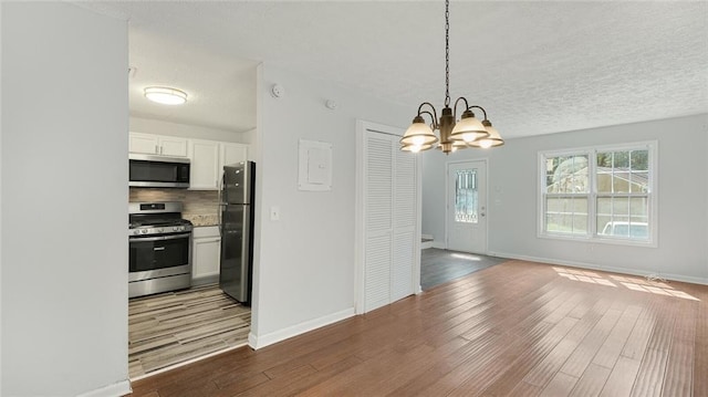 6964 Oakhill Cir, Austell, GA 30168 - unfurnished dining area featuring wood finished floors, a chandelier, baseboards, and a textured ceiling
