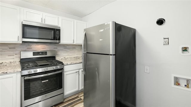 6964 Oakhill Cir, Austell, GA 30168 - kitchen with stainless steel appliances, tasteful backsplash, white cabinets, light stone counters, and wood finished floors