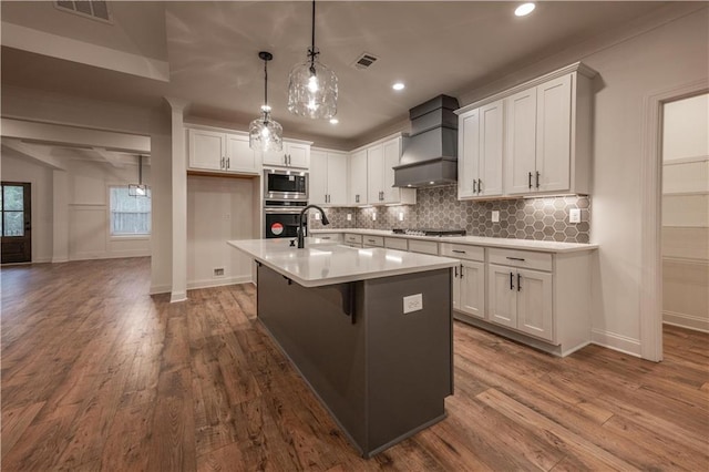 kitchen featuring white cabinets, wood-type flooring, stainless steel appliances, and custom exhaust hood