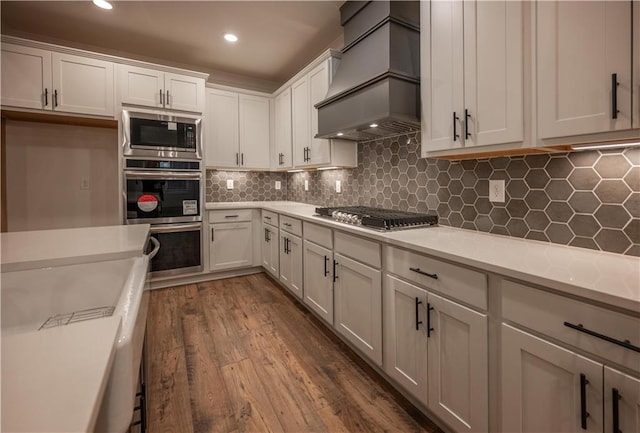 kitchen featuring white cabinets, custom range hood, and appliances with stainless steel finishes