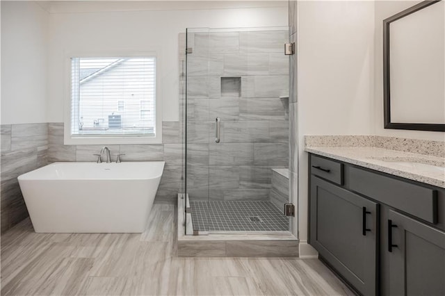 bathroom with vanity, tile walls, and independent shower and bath