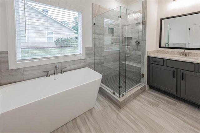 bathroom featuring vanity, tile walls, and plus walk in shower