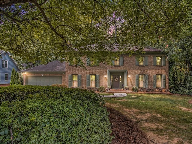 colonial home featuring a garage and a front lawn