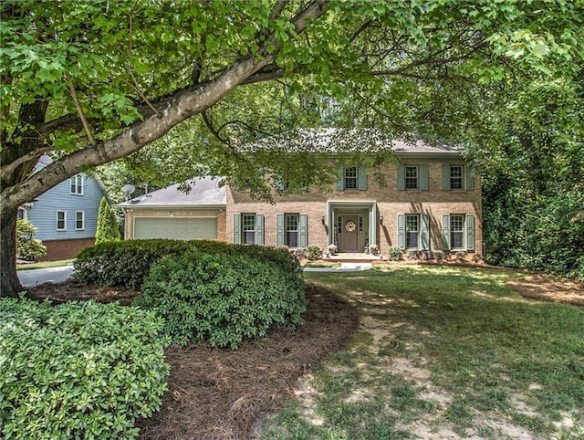 colonial house featuring a front yard and a garage