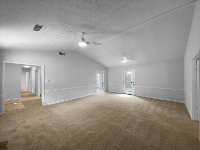 carpeted spare room featuring a textured ceiling, ceiling fan, and vaulted ceiling