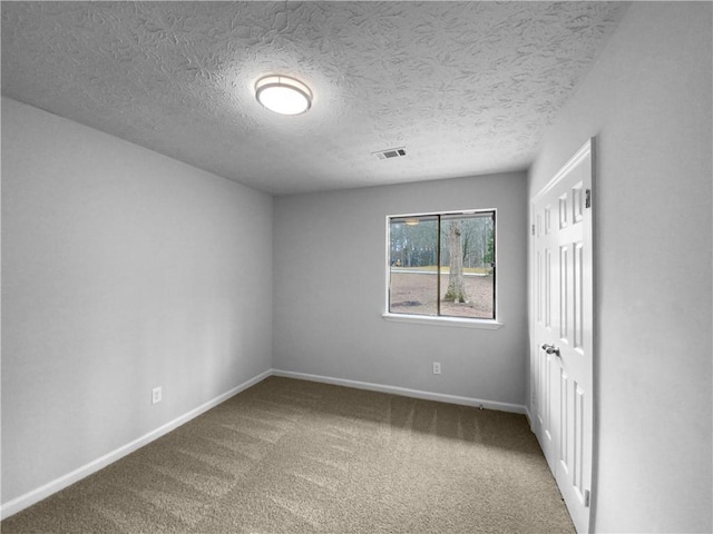 spare room featuring a textured ceiling and carpet