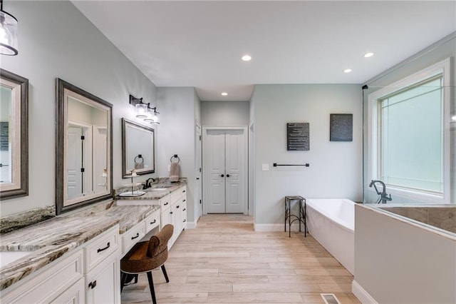 7269 Tyree Rd, Winston, GA 30187 - bathroom with a soaking tub, wood finished floors, vanity, and recessed lighting